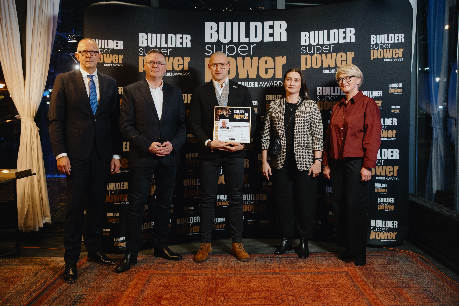 Pięc osób stoi na tle banera Biulder super power